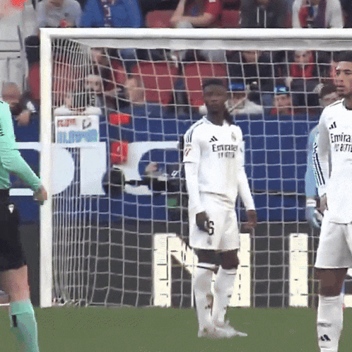a soccer player wearing a white emirates jersey stands in front of a goal