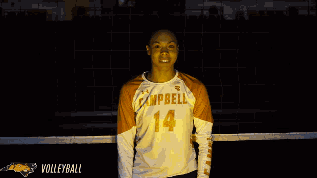 a man wearing a campbell 14 jersey stands in front of a net