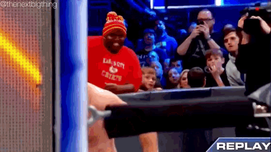 a man wearing a red shirt that says ' lil ' boy ' on it stands in front of a crowd