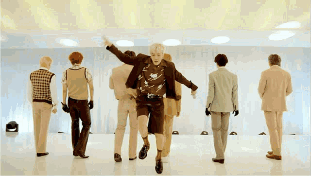 a group of men in suits are dancing on a white floor