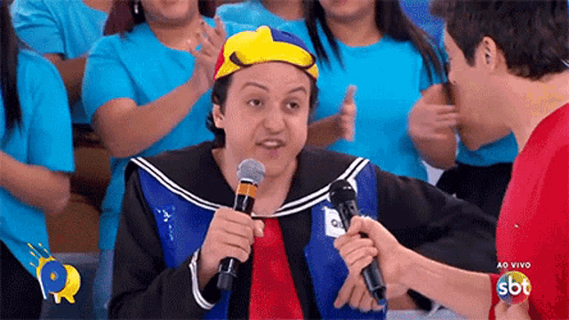 a man in a costume is holding a microphone and talking to another man in a red shirt ..