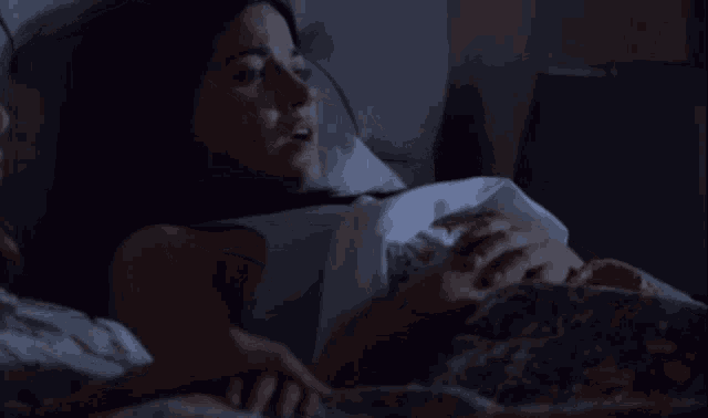 a woman laying in a bed with a blanket on her stomach