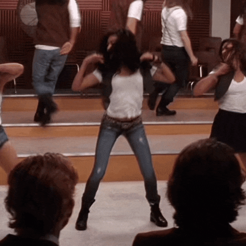 a group of people are dancing on a stage and one of them is wearing jeans