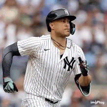 a baseball player wearing a helmet and headphones is running on the field .