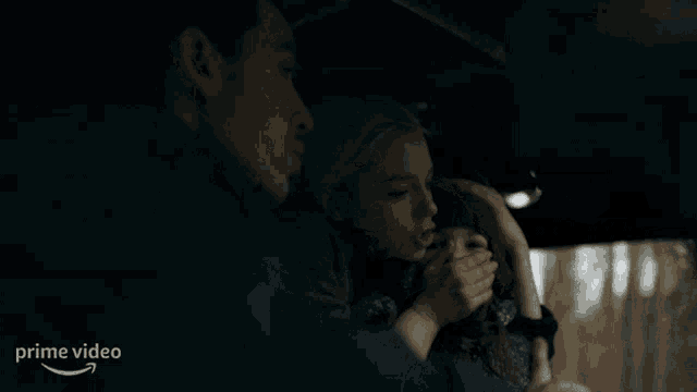 a woman covering a child 's mouth in a car with a prime video arrow