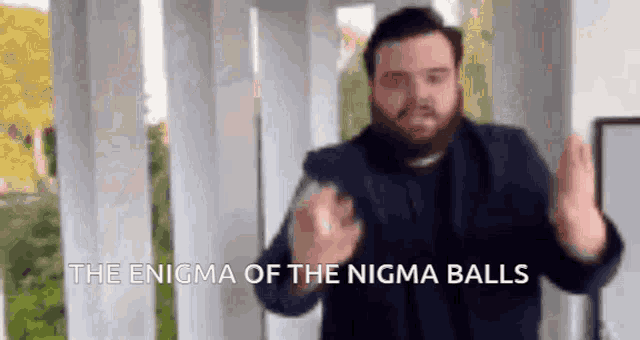 a man with a beard is standing in front of a sign that says " the enigma of the nisma balls "