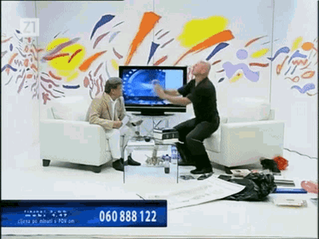 a man is dancing in front of a television with the number 060 888 122 on the bottom