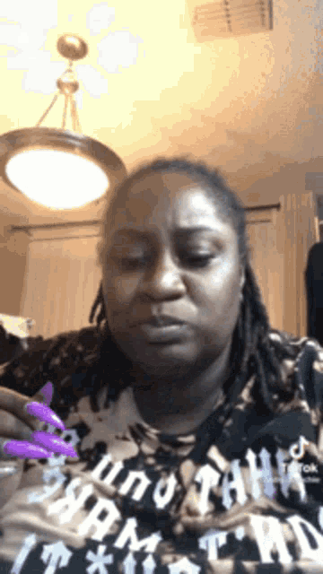 a woman with long purple nails is wearing a shirt that says " i am "