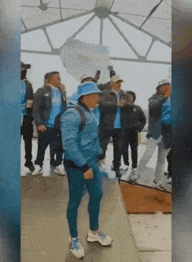 a man in a blue hat is dancing in front of a group of people