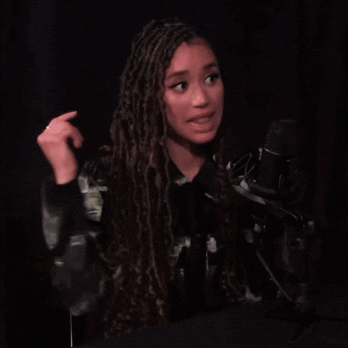 a woman singing into a microphone with a ring on her finger
