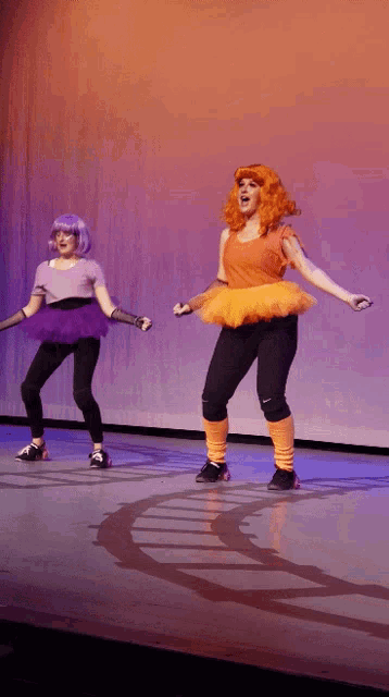 two women are dancing on a stage and one is wearing a tutu
