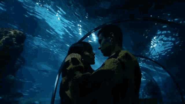 a man and a woman are looking at a fish tank