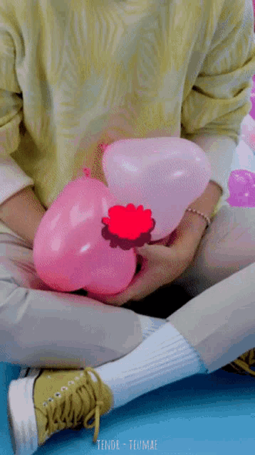 a person holding a pink heart shaped balloon