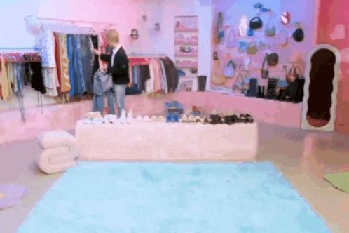 a woman is standing in front of a table full of clothes and shoes