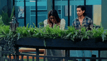 a man and a woman standing next to each other in front of a planter