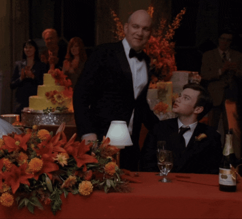 two men are sitting at a table with a bottle of champagne