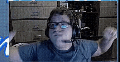 a man wearing headphones and glasses is dancing in front of a computer screen .