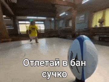 a baby is running towards a rugby ball in a room