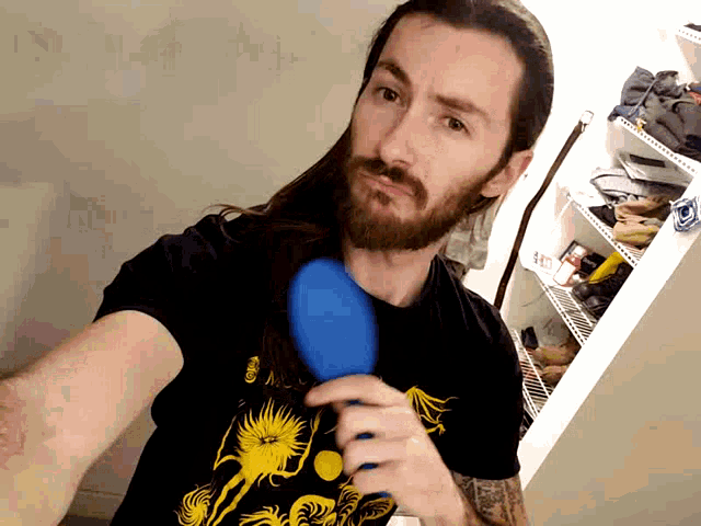 a man with long hair and a beard is holding a blue brush