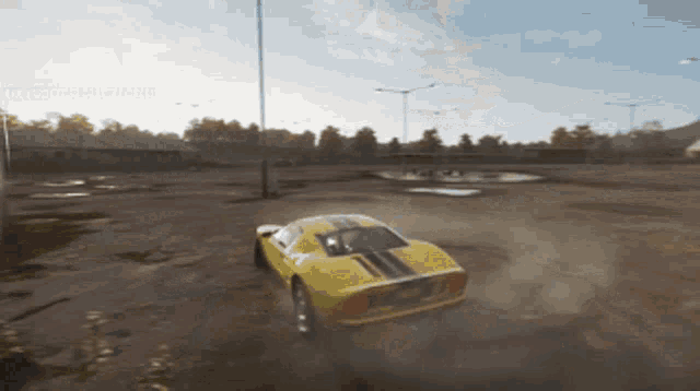a yellow car is driving through a dirt field