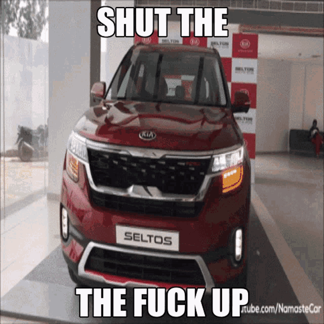 a red kia seltos is displayed in a showroom with the caption shut the the fuck up