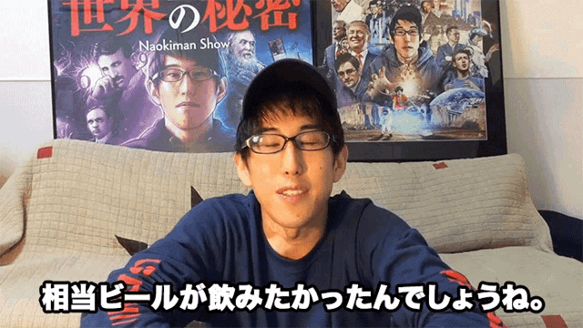 a man sitting on a couch with a naokiman show poster behind him