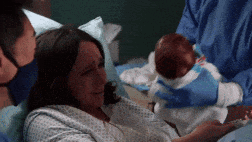 a woman in a hospital gown is holding a newborn baby