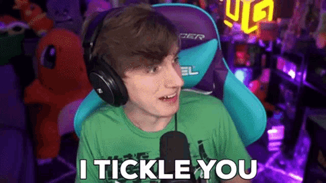 a young man wearing headphones and a green shirt is sitting in front of a microphone and saying i tickle you