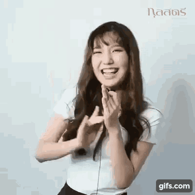 a young woman is laughing and clapping her hands .