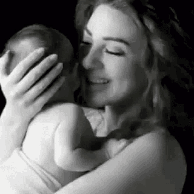 a woman is holding a baby in her arms and kissing it .