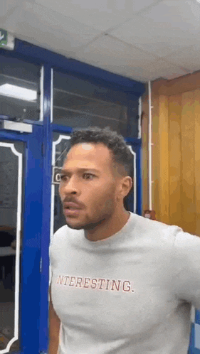 a man wearing a t-shirt that says `` interesting '' is standing in front of a door .