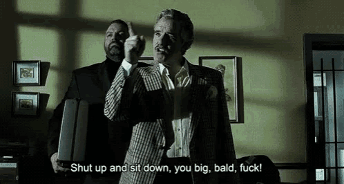a man holding a briefcase says shut up and sit down you big bald fuck