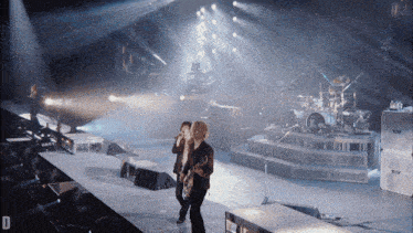 a man playing a guitar on a stage with the letter d in the lower right corner