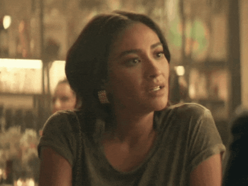 a woman wearing a gray shirt and earrings looks to the side