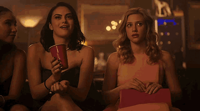 a woman in a pink dress is holding a red cup that says coca cola