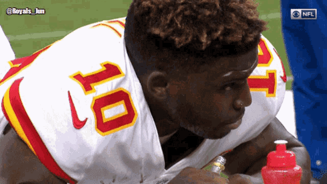 a football player with the number 10 on his jersey is drinking from a red bottle