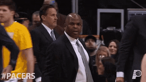 a man in a suit and tie stands in front of a crowd with #pacers written on the bottom right