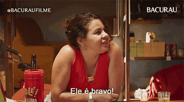 a woman in a red tank top is sitting at a table with a red container that says ele e bravo