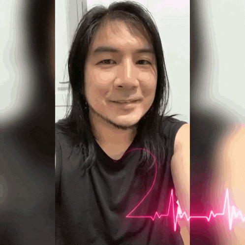 a man with long hair and a beard is wearing a black shirt with a pink heartbeat on it