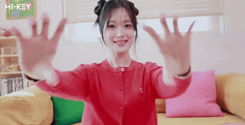 a girl in a red sweater is sitting on a couch with her hands outstretched