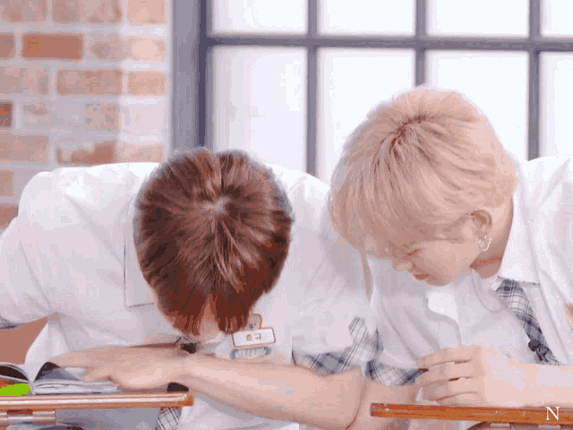 a boy with a name tag that says ' n ' on it sits next to another boy