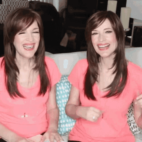 two women wearing pink shirts are laughing together