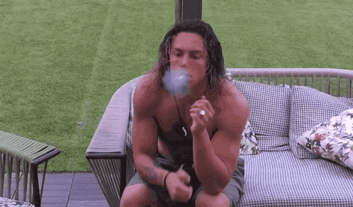 a man is sitting on a couch smoking a cigarette