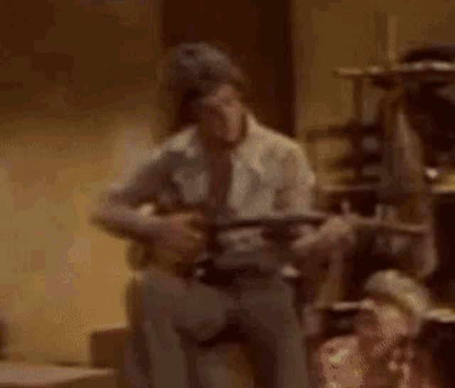 a man is sitting on a couch playing a guitar in a dark room .