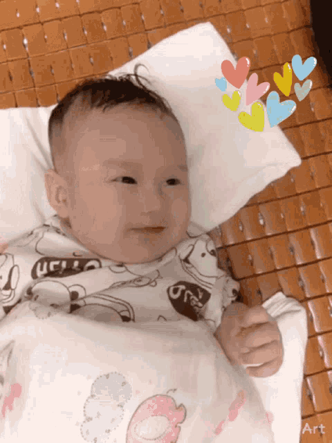 a baby wearing a shirt that says ucl is laying on a white pillow