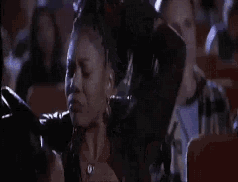 a woman is sitting in a crowd of people watching a movie and dancing .