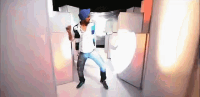 a man in a blue hat and white shirt is dancing in a room