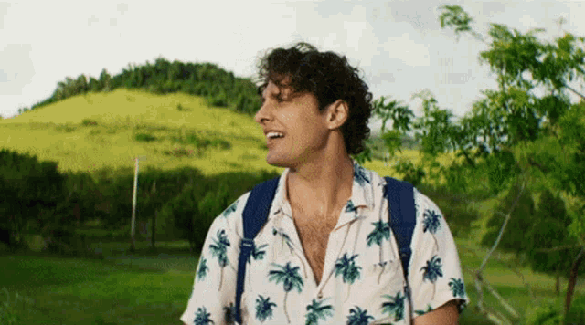 a man wearing a shirt with palm trees on it is smiling