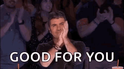 a man is sitting in front of a crowd of people applauding and saying good for you .