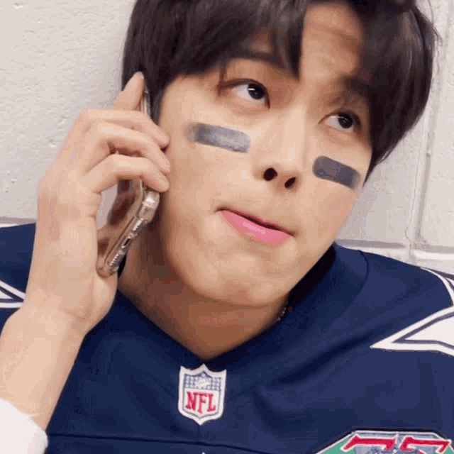 a man in an nfl jersey talking on a cell phone